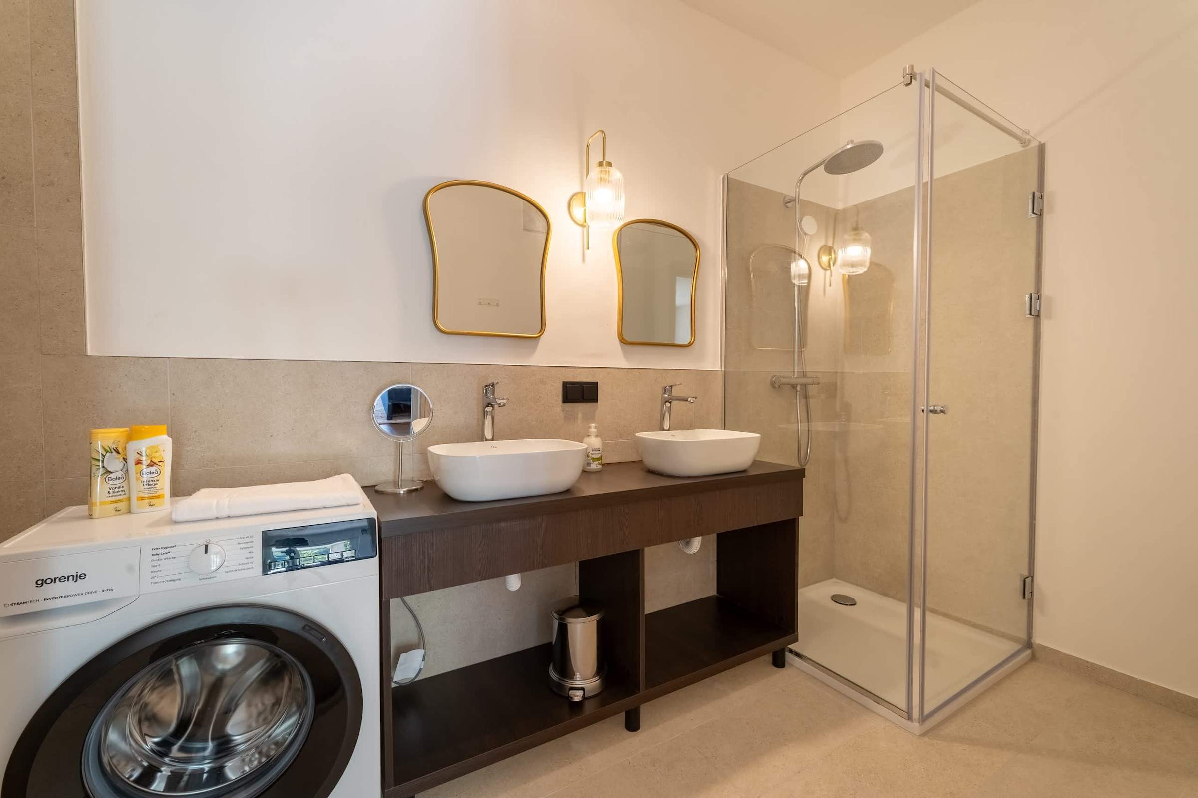 Bathroom with twin washbasins, walk-in shower and washing machine