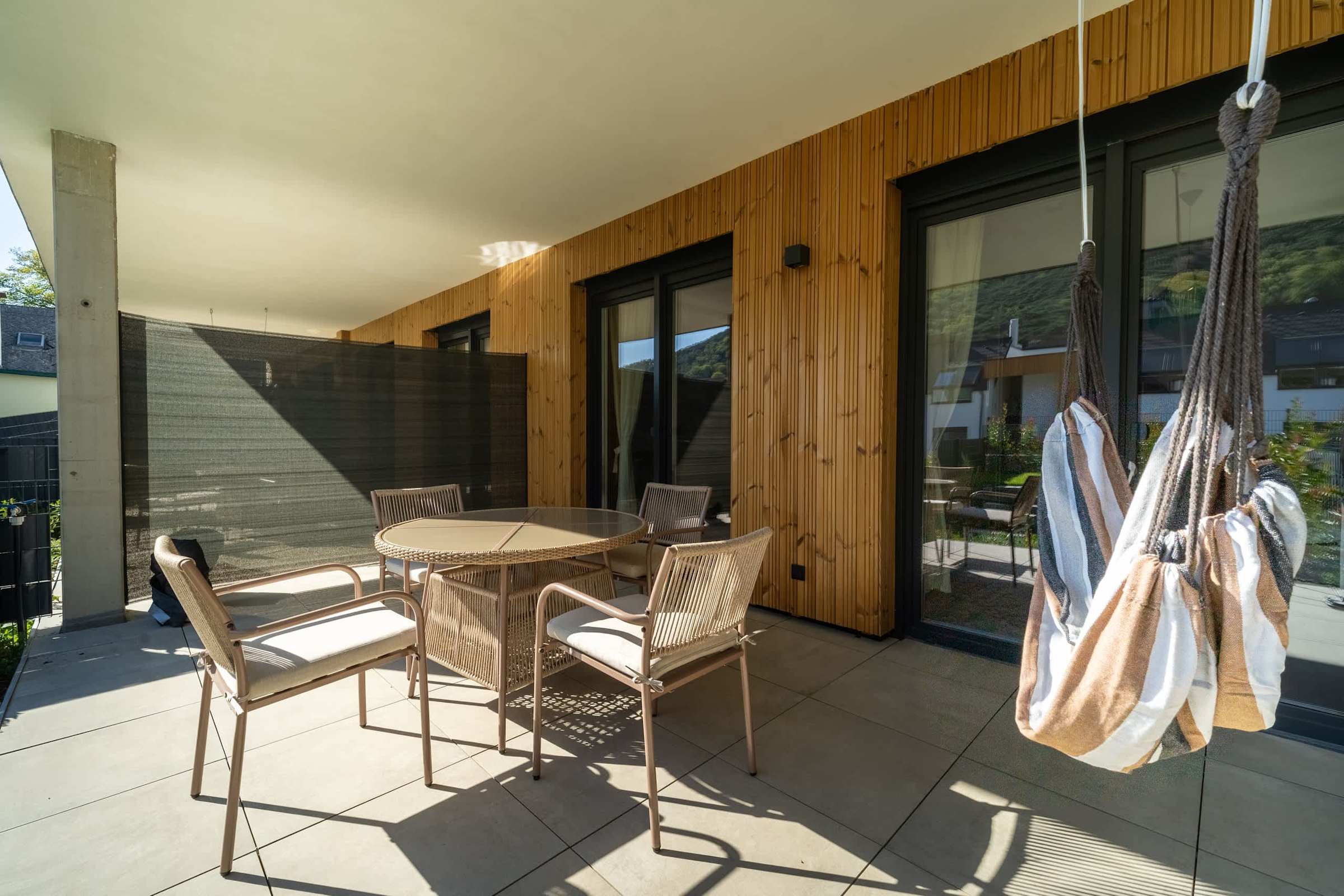 Covered terrace with dining table and hanging chair